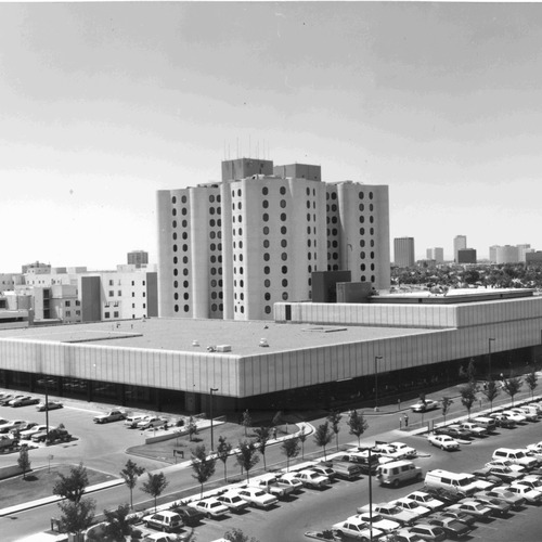 View of Good Samaritan Hospital from across the street showing Goldberg tower, parking structure and cars parked in a surface lot.