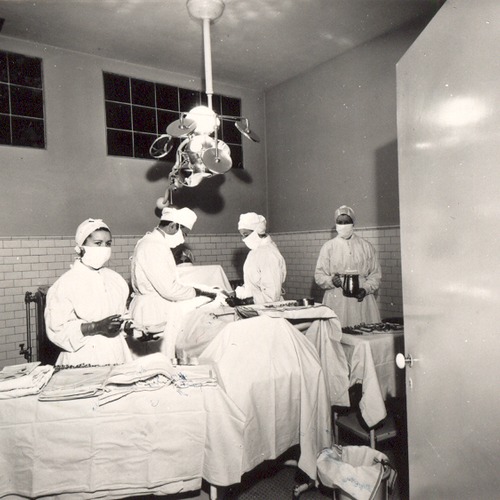 Operating room with four medical professionals operating on an unseen patient.